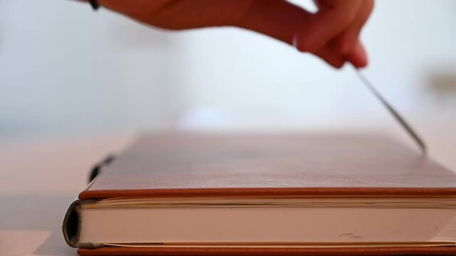 SLOW MOTION shallow focus side shot of a leather bound book being opened by pulling on the book ribbon marker