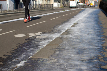silhouette of anonymous female jogger running on winter city bicycle lanes