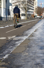 back-sided anonymous man riding bicycle on winter bicycle lanes