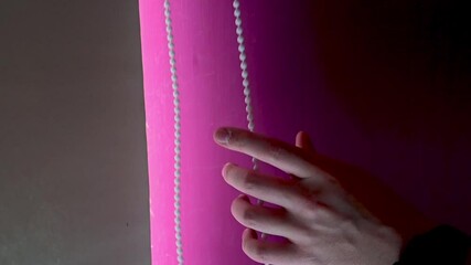 SLOW MOTION CLOSE UP of hands pulling open a roller blind