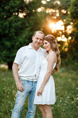 Young loving couple hugging on the green grass in the park. Beautiful woman and man gently touch each other. Beautiful couple in love. girl in the dress and the guy in the shirt. valentines day