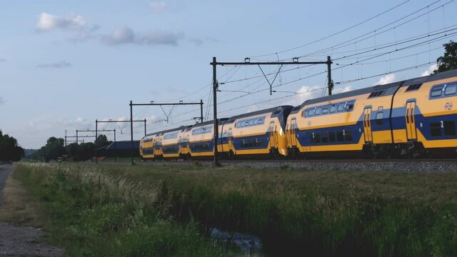 Dutch intercity train passing with a blue sky with clouds