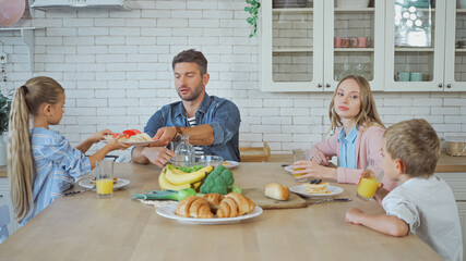 Family sitting near breakfast with orange juice in kitchen