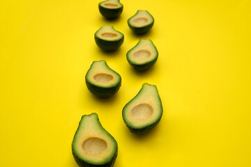 Avocado slices are arranged on a yellow background. pieces of fruit create the illusion of walking