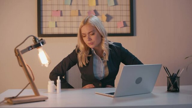 blonde businesswoman suffering from stomach ache in office