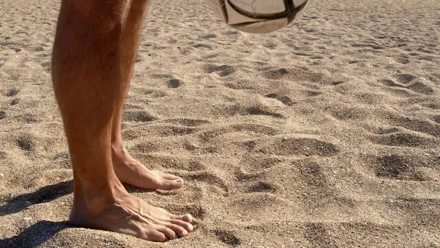 Football soccer game on the beach. Male feet juggling the ball on the sandy sea beach, 4k slow motion