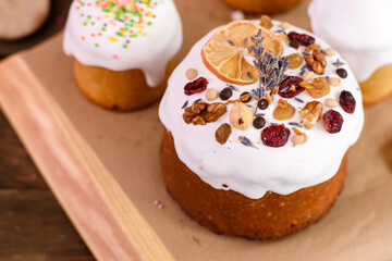 Festive cakes with white glaze, nuts and raisins with Easter eggs on the festive table