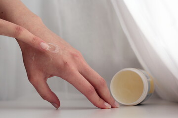 Closeup of a person applying vaseline (petroleum jelly). Concept of slugging - Korean skin care...