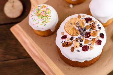Festive cakes with white glaze, nuts and raisins with Easter eggs on the festive table