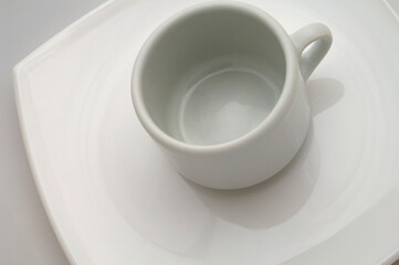 Taza de café sobre un plato. Un único color blanco. Foto de estudio.