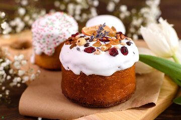 Festive cakes with white glaze, nuts and raisins with Easter eggs on the festive table