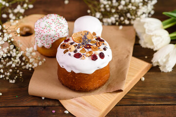 Festive cakes with white glaze, nuts and raisins with Easter eggs on the festive table
