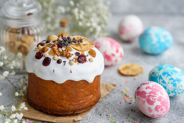 Festive cakes with white glaze, nuts and raisins with Easter eggs on the festive table