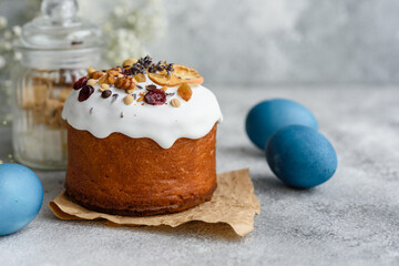 Festive cakes with white glaze, nuts and raisins with Easter eggs on the festive table
