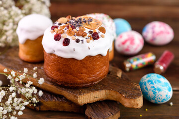 Festive cakes with white glaze, nuts and raisins with Easter eggs on the festive table