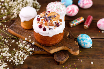 Festive cakes with white glaze, nuts and raisins with Easter eggs on the festive table