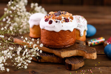 Festive cakes with white glaze, nuts and raisins with Easter eggs on the festive table