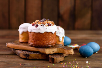 Festive cakes with white glaze, nuts and raisins with Easter eggs on the festive table