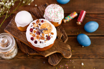Festive cakes with white glaze, nuts and raisins with Easter eggs on the festive table