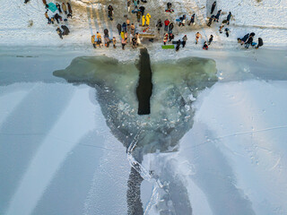 Aerial drone view. Epiphany swimming in an ice-hole in the river. Sunny frosty winter morning.