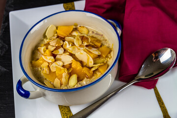 Overnight oats bircher topped with toasted almond flakes, peach and honey elevated.
