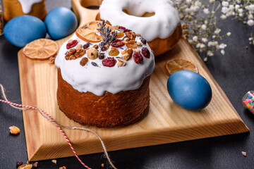 Festive cakes with white glaze, nuts and raisins with Easter eggs on the festive table