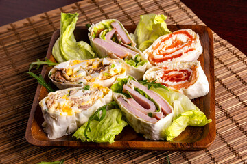 Sliced spring rolls with salmon, tuna fish, ham, egg and green vegetables.