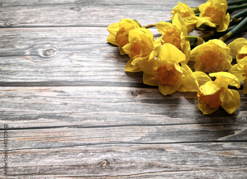 Yellow daffodils on wooden surface shot from above with space for text. Flat lay, top view, copy space. Easter and Mother's Day concept. Floral background.