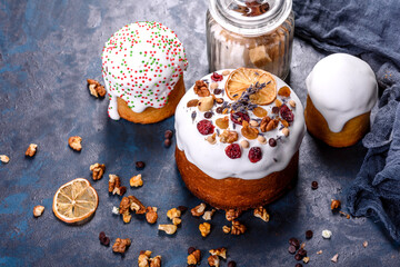 Festive cakes with white glaze, nuts and raisins with Easter eggs on the festive table