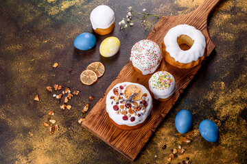 Fototapeta na wymiar Festive cakes with white glaze, nuts and raisins with Easter eggs on the festive table