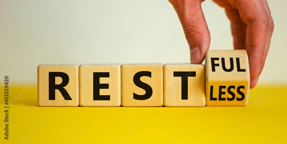 Fototapete restless or restful symbol. businessman turns the wooden cube, changes the word 'restless' to 'restf