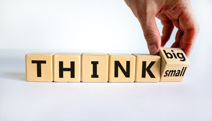 Think small or big concept. Businessman turns wooden cubes, changes words 'think small' to 'think...
