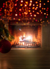 Xmas at home. Red ball on tree branch, bokeh burning fireplace background. Copy space.