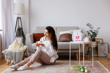 young mother in the living room with a card and flowers