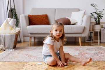 Obraz na płótnie Canvas Little girl sitting on the floor in the living room