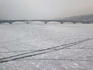 Bridge over a frozen river in Kiev in fog. Aerial drone view. Foggy winter morning.