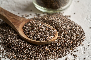 Chia seeds on a wooden spoon on a white background