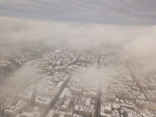 Fog over the snowy Kiev city. Aerial drone view. Foggy winter day.