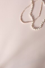 Two natural pearl necklaces on a smoky-pink background. Flat lay