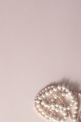 Two natural tangled pearl necklaces on a smoky-pink background. Flat lay