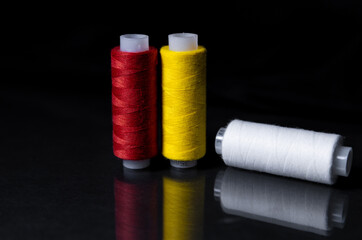 colored skeins of thread on a dark background and a mirror surface