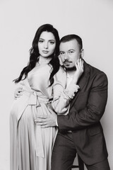 Pregnancy photoshoot of a beautiful couple, future parents in a gray dress and suit