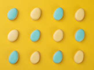 Blue and yellow easter egg cookies over yellow background