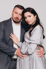 Pregnancy photoshoot of a beautiful couple, future parents in a gray dress and suit