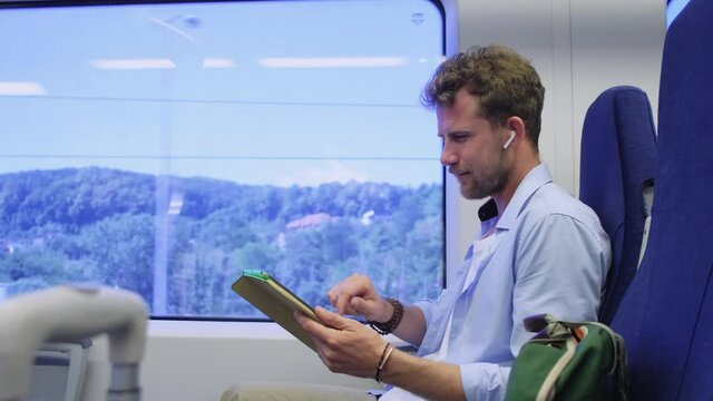 man is travelling by train, viewing pictures in tablet