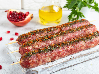 raw beef lamb lula kebab on wooden skewer on a board, close up