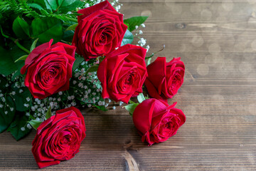 Red roses bouquet on the wooden table in sunlights. Nice gift for Valentine's day or Mother's day.