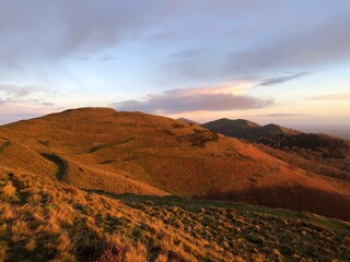 British camp iron age hill fort showing hill ramparts and walking paths at sunrise. Hills leading to Worcestershire beacon in the background.