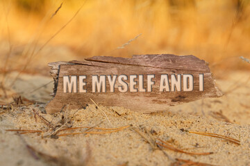 On the sand against a background of yellow grass, a signboard with the inscription - ME MYSELF AND I