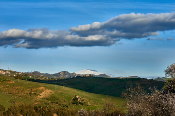 The snowy silhouette of the Etna volcano seen from the countryside of Central Sicily near Nicosia on a beautiful sunny day